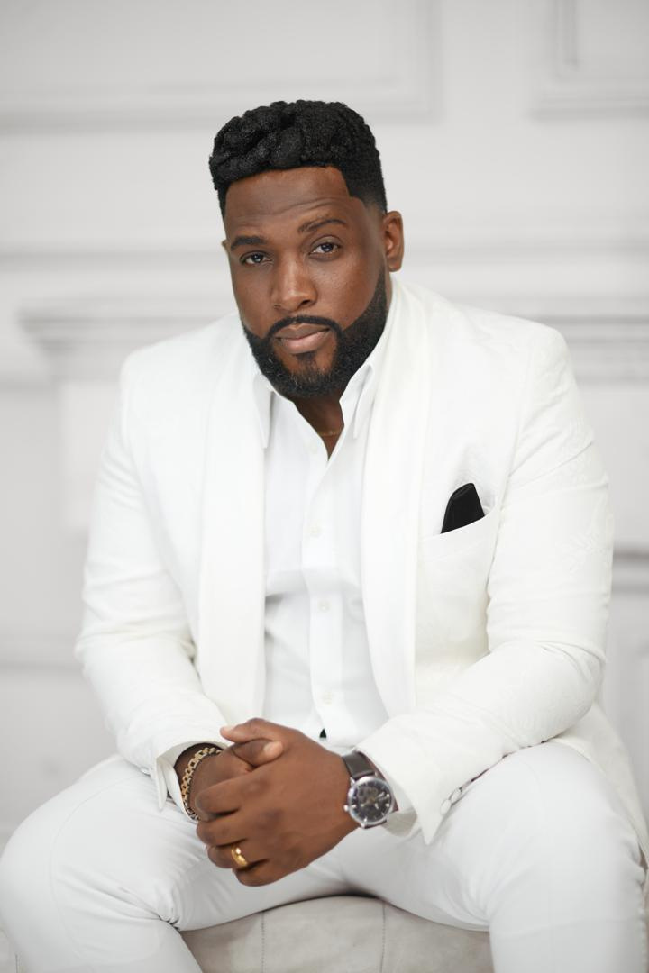 Portrait du Prophète Grâce Muamba Jey en costume blanc, mains jointes